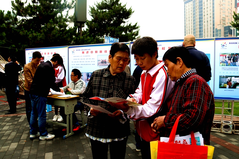 渭南市2016年职业教育活动周-陕西铁路工程职业技术学院咨询展位前志愿者向市民宣传职业教育-04_副本.jpg